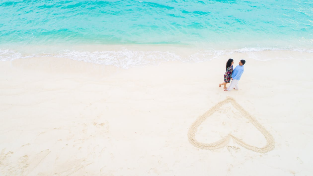 Two People Standing Beside Each Other Near Beach Shore