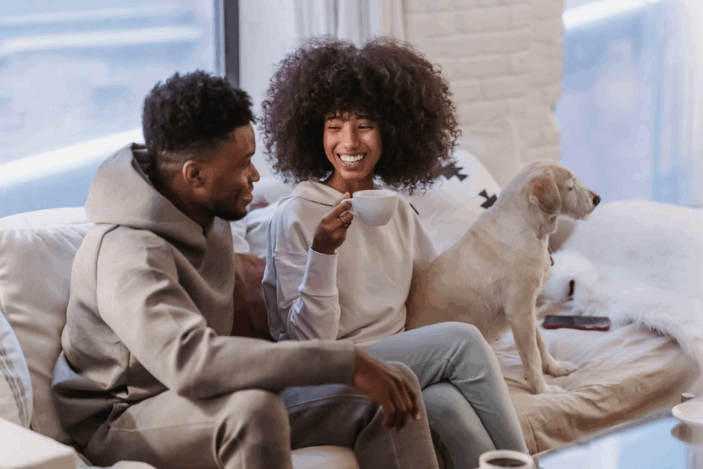 Loving black couple communicating while sitting on sofa with adorable dog