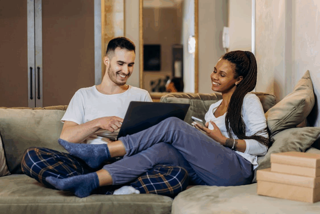 Man and Woman Sitting on Green Sofa using Laptop