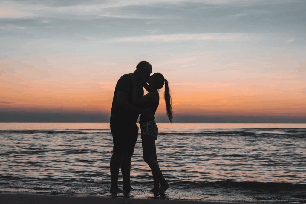 Man and Woman Kissing on Beach during Sunset