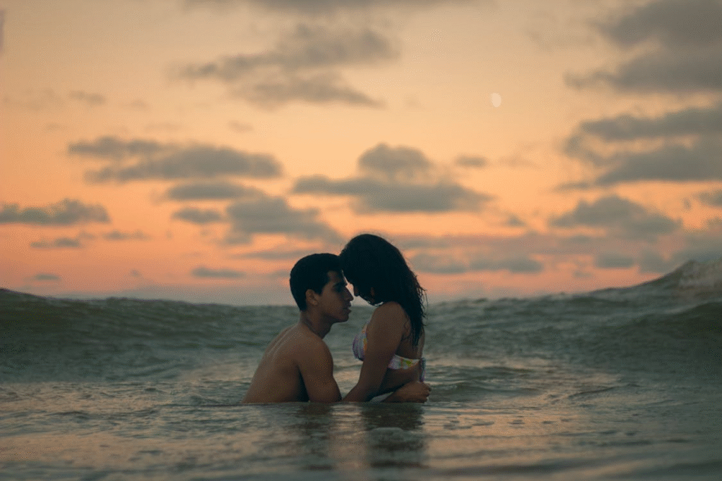 A couple embraces in the ocean during a romantic sunset, capturing love and intimacy