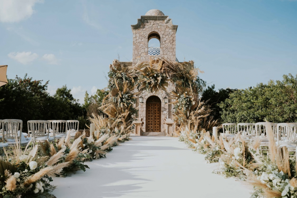 Beautiful outdoor wedding aisle with floral decorations leading to a stone building under a clear sky