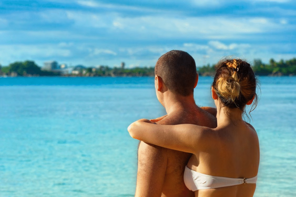A couple embracing and enjoying the view at a sunny tropical beach, symbolizing love and relaxation