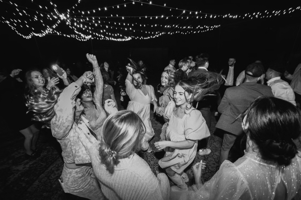 Lively black and white photo capturing joyful dancing at a night party under twinkling lights.