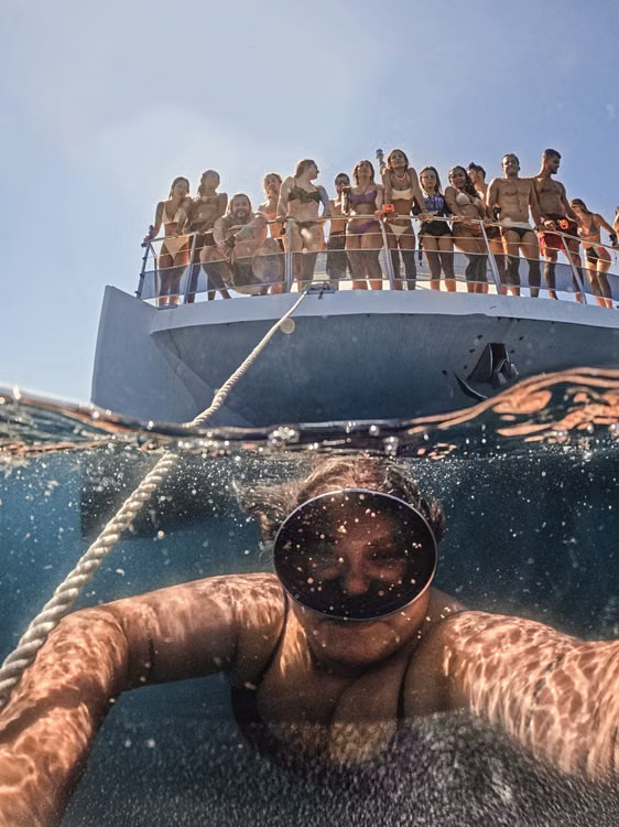 A snorkeler swims underwater as a group enjoys leisure time on a boat.